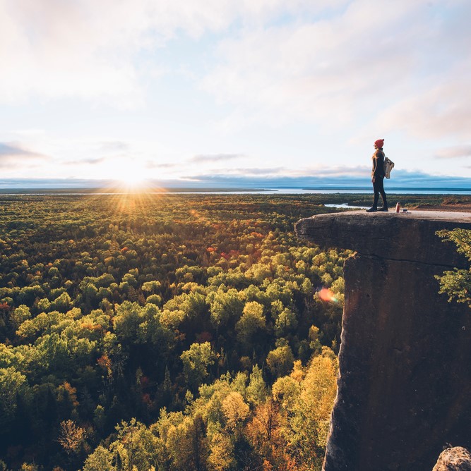 Some one looking off a cliff into a sea of trees