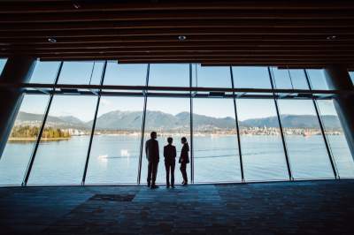 Three people looking out at a glass with views of Vancouver's mountains