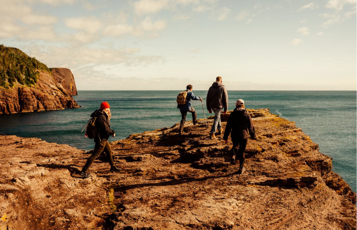 Four people exploring at top of cliff over the ocean