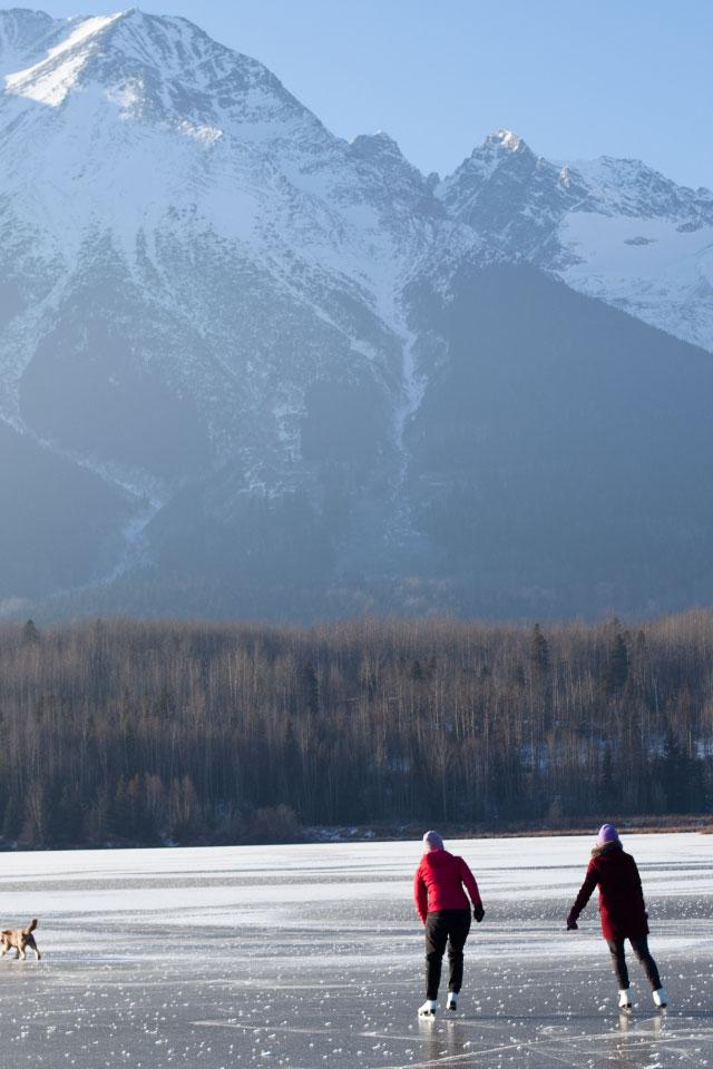 Deux personnes qui patinent devant des montagnes.