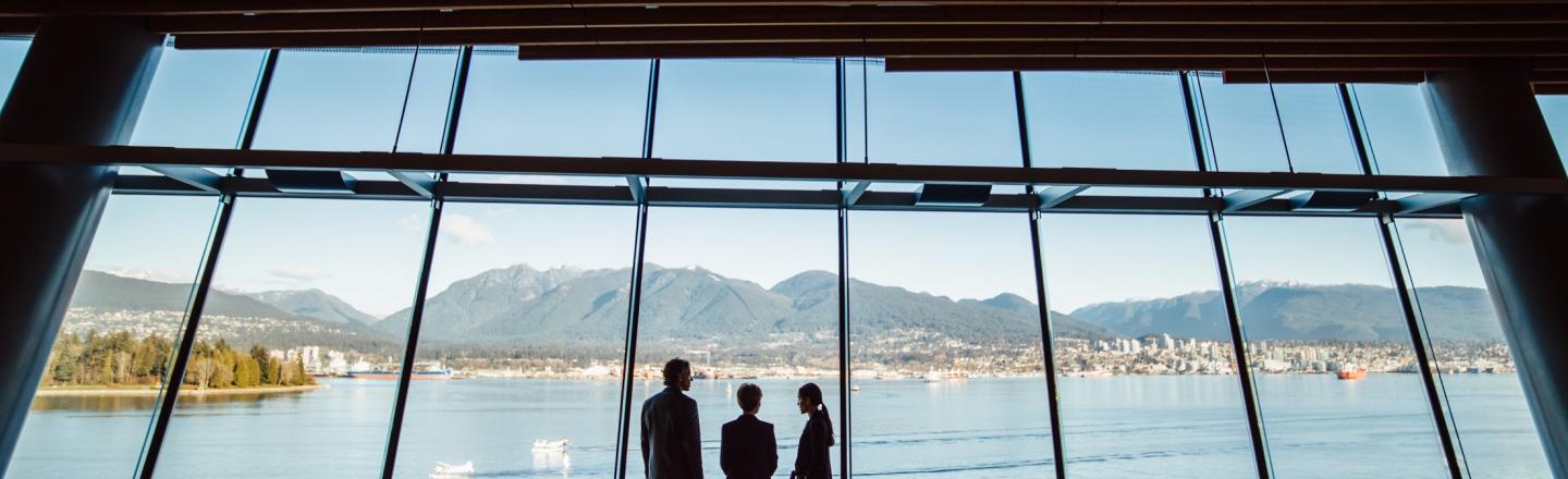 Three people looking out at a glass with views of Vancouver's mountains