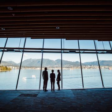 Three people looking out at a glass with views of Vancouver's mountains